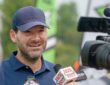 Former Dallas Cowboys quarterback Tony Romo smiles as he answers questions in front of television microphones.