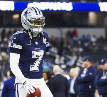 Dallas Cowboys cornerback Trevon Diggs stands with a football in his hand during pregame warmups in a navy No. 7 jersey.