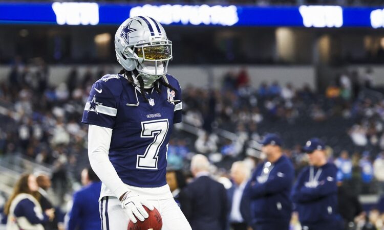 Dallas Cowboys cornerback Trevon Diggs stands with a football in his hand during pregame warmups in a navy No. 7 jersey.