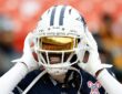 Dallas Cowboys cornerback Trevon Diggs adjusts his helmet during warmups, a gold visor covering his eyes.
