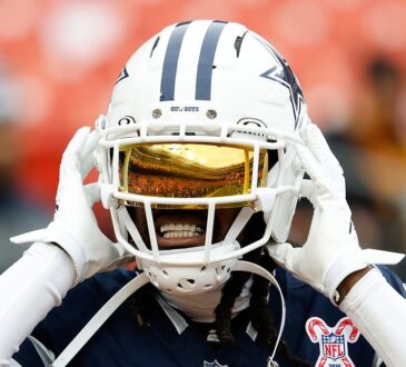 Dallas Cowboys cornerback Trevon Diggs adjusts his helmet during warmups, a gold visor covering his eyes.