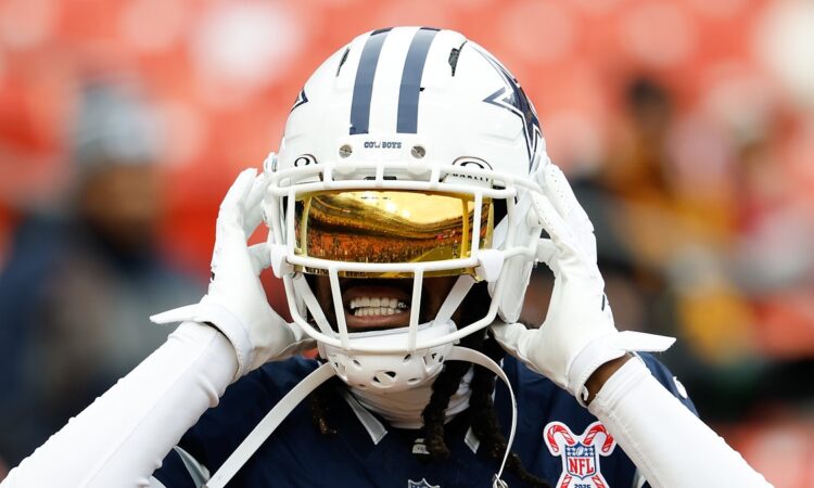 Dallas Cowboys cornerback Trevon Diggs adjusts his helmet during warmups, a gold visor covering his eyes.