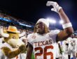 Texas Longhorns linebacker Ty’Anthony Smith raises an arm and smiles beside the Texas mascot after the game.