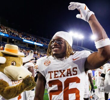 Texas Longhorns linebacker Ty’Anthony Smith raises an arm and smiles beside the Texas mascot after the game.