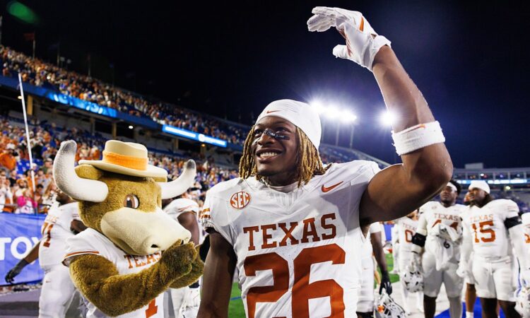 Texas Longhorns linebacker Ty’Anthony Smith raises an arm and smiles beside the Texas mascot after the game.