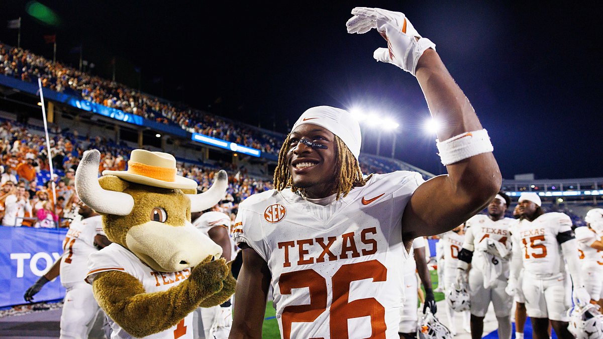Texas Longhorns linebacker Ty’Anthony Smith raises an arm and smiles beside the Texas mascot after the game.