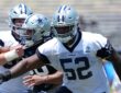 Dallas Cowboys guard Tyler Booker extends his arms during a training camp drill in a No. 52 practice jersey.
