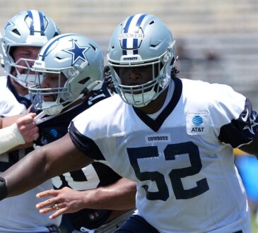 Dallas Cowboys guard Tyler Booker extends his arms during a training camp drill in a No. 52 practice jersey.