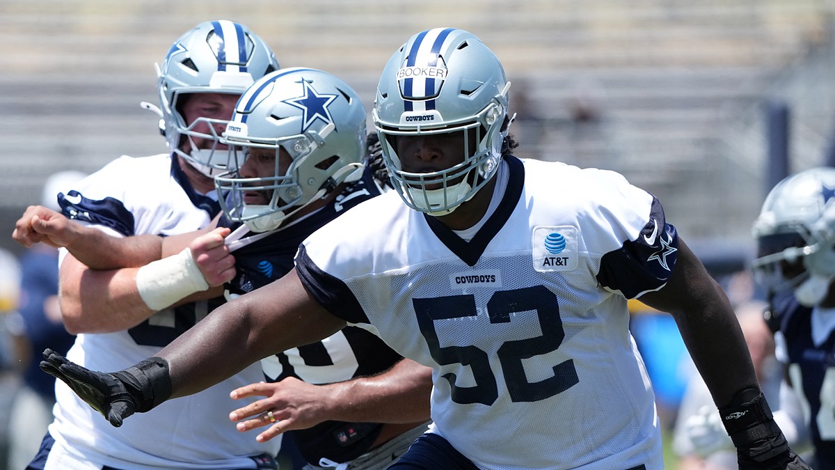 Dallas Cowboys guard Tyler Booker extends his arms during a training camp drill in a No. 52 practice jersey.