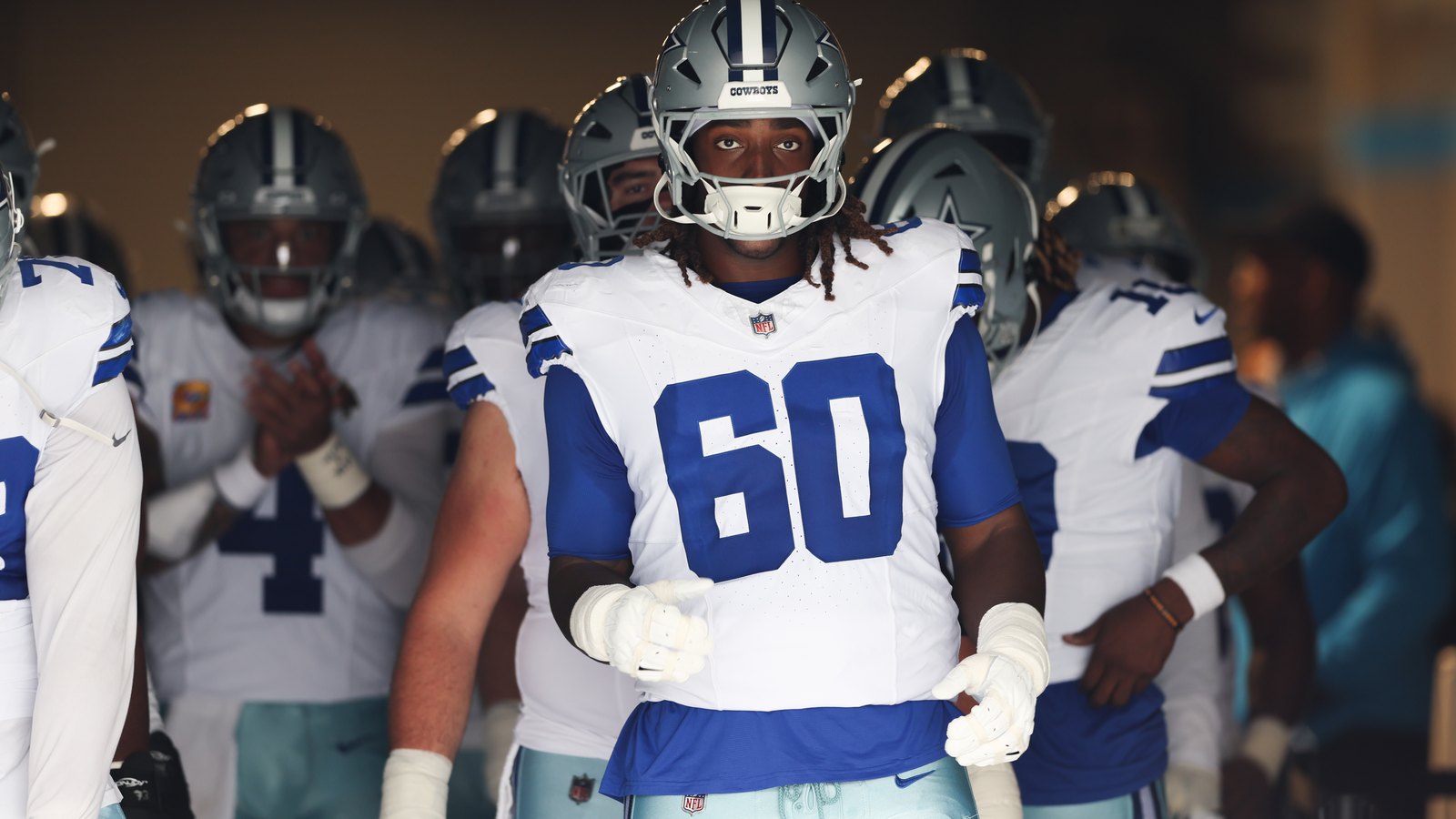 Dallas Cowboys offensive tackle Tyler Guyton wears No. 60 and walks through the stadium tunnel with teammates before kickoff.