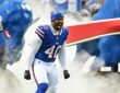 Buffalo Bills linebacker Von Miller shouts as he runs onto the field through smoke in a blue No. 40 jersey and knit cap.