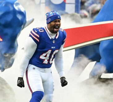 Buffalo Bills linebacker Von Miller shouts as he runs onto the field through smoke in a blue No. 40 jersey and knit cap.