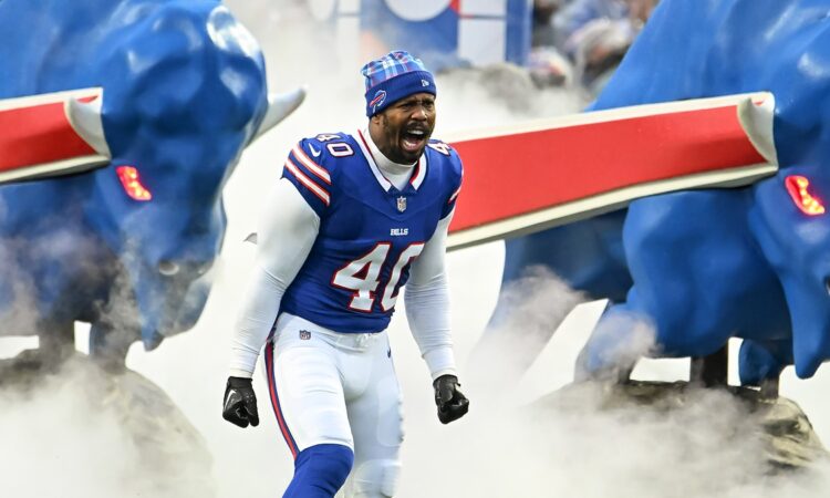 Buffalo Bills linebacker Von Miller shouts as he runs onto the field through smoke in a blue No. 40 jersey and knit cap.