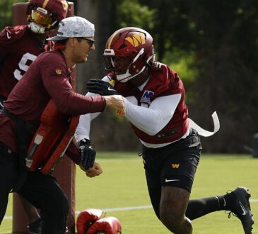 Washington Commanders linebacker Von Miller drives past a coach holding a blocking pad during a training camp drill.