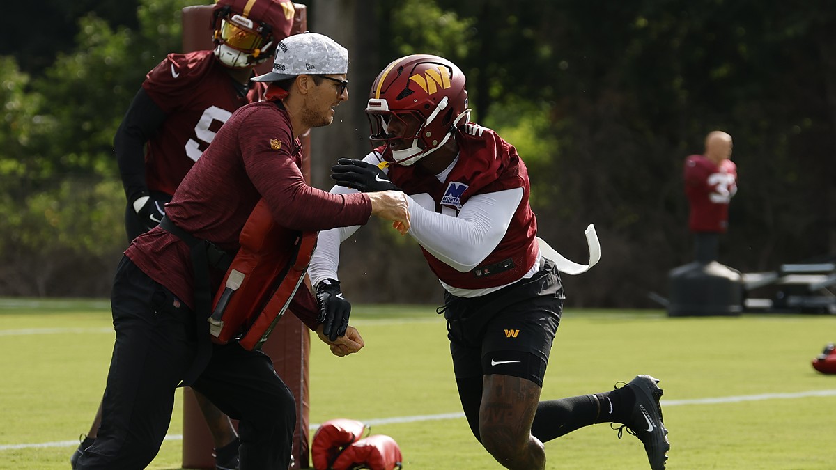 Washington Commanders linebacker Von Miller drives past a coach holding a blocking pad during a training camp drill.