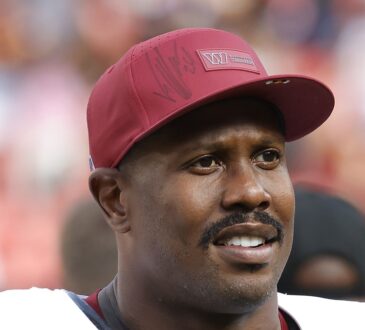 Washington Commanders outside linebacker Von Miller smiles in a burgundy team cap as he walks off the field.