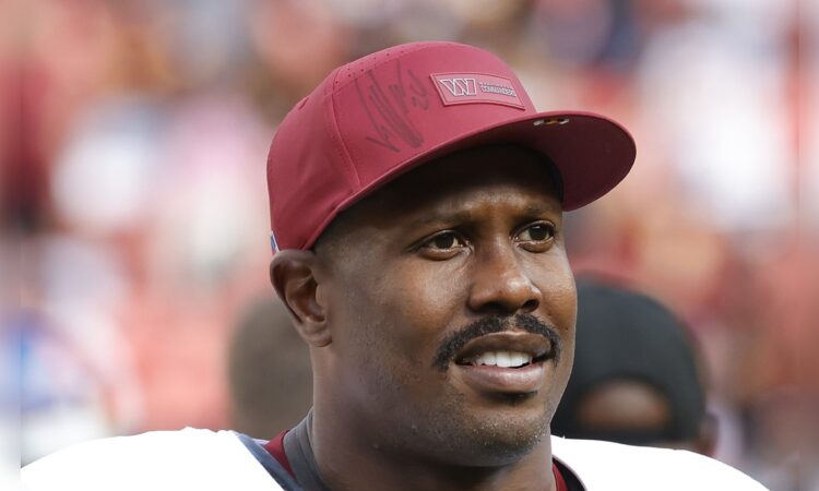Washington Commanders outside linebacker Von Miller smiles in a burgundy team cap as he walks off the field.