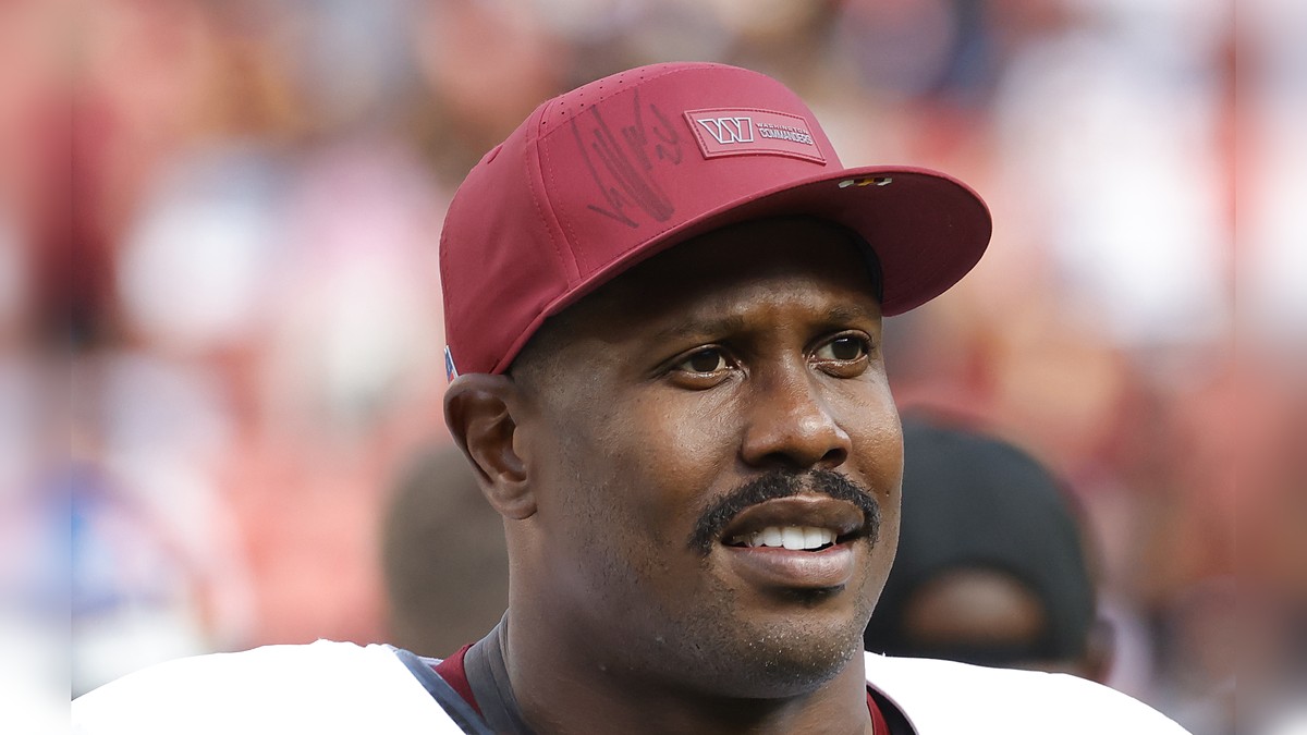 Washington Commanders outside linebacker Von Miller smiles in a burgundy team cap as he walks off the field.