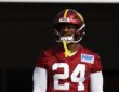 Washington Commanders outside linebacker Von Miller walks onto the practice field in a red No. 24 jersey and helmet.