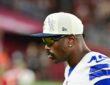 Dallas Cowboys edge rusher Von Miller looks on from the sideline in a cap and sunglasses at State Farm Stadium.