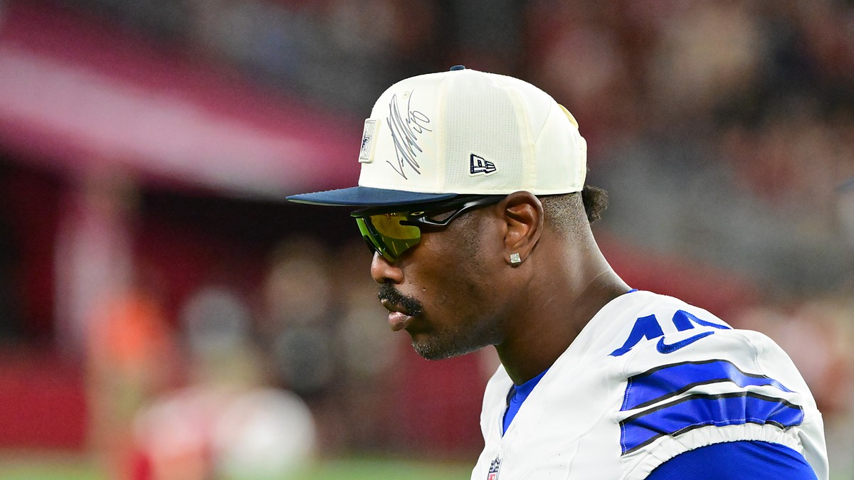Dallas Cowboys edge rusher Von Miller looks on from the sideline in a cap and sunglasses at State Farm Stadium.