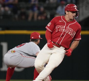 Texas Rangers left fielder Wyatt Langford rounds second in a red Tejas jersey as an Angels infielder crouches nearby.
