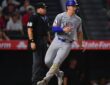 Texas Rangers left fielder Wyatt Langford jogs across the plate to score as the umpire watches behind him.