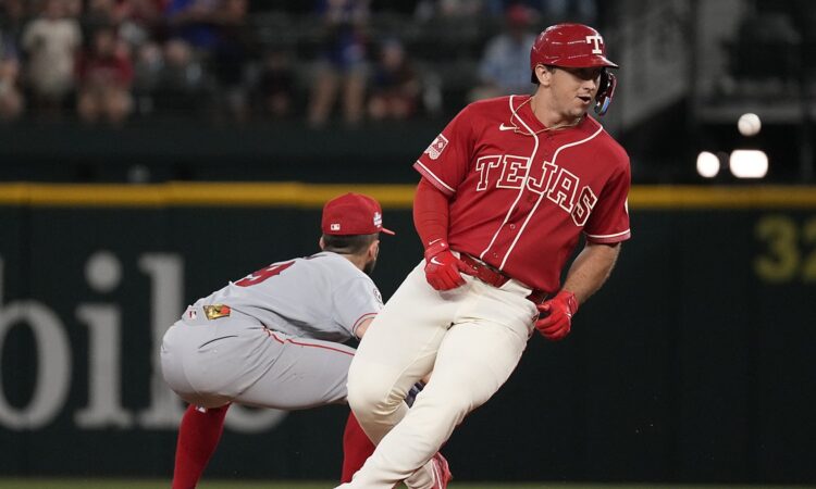 Texas Rangers left fielder Wyatt Langford runs up the baseline as Angels pitcher Ryan Johnson throws to first.