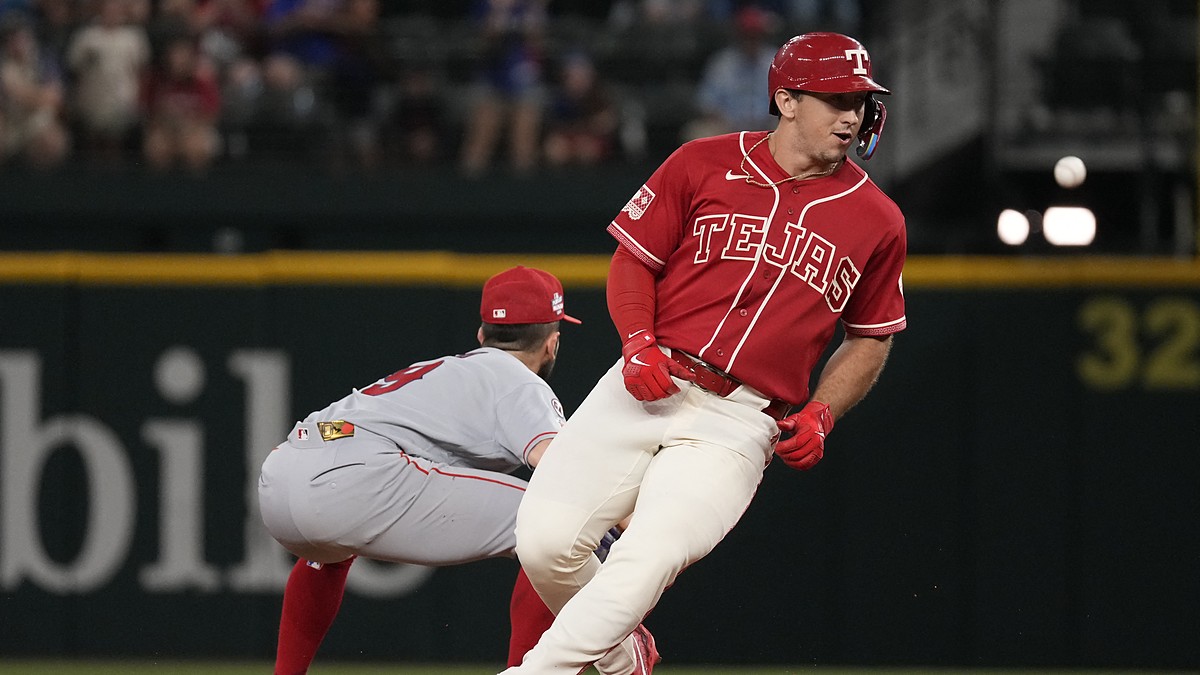 Texas Rangers left fielder Wyatt Langford runs up the baseline as Angels pitcher Ryan Johnson throws to first.