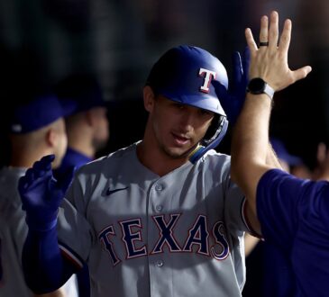 Texas Rangers left fielder Wyatt Langford exchanges high fives with teammates in the dugout after a home run.