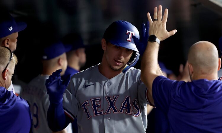 Texas Rangers left fielder Wyatt Langford exchanges high fives with teammates in the dugout after a home run.