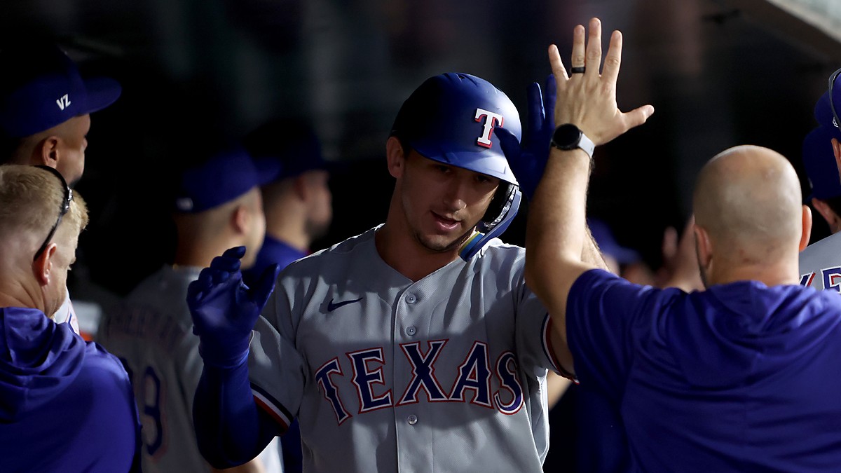 Texas Rangers left fielder Wyatt Langford exchanges high fives with teammates in the dugout after a home run.