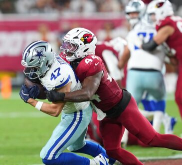 Dallas Cowboys tight end Zack Kuntz holds the ball as Cardinals linebacker Owen Pappoe wraps him up.