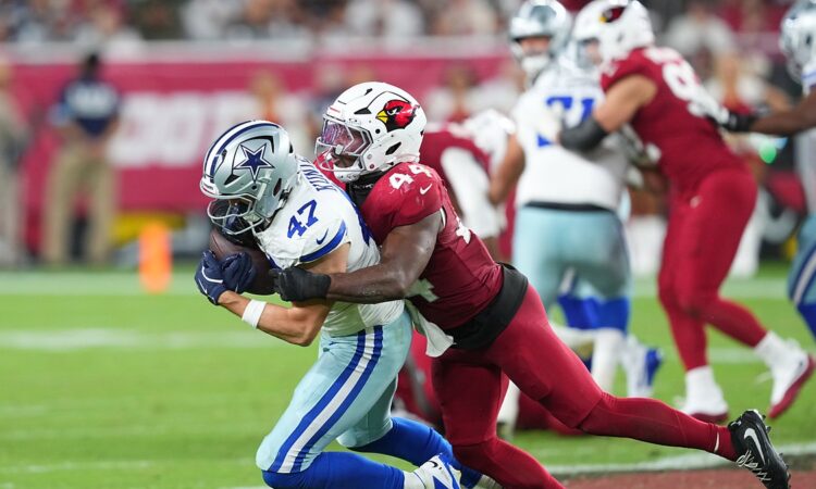 Dallas Cowboys tight end Zack Kuntz holds the ball as Cardinals linebacker Owen Pappoe wraps him up.