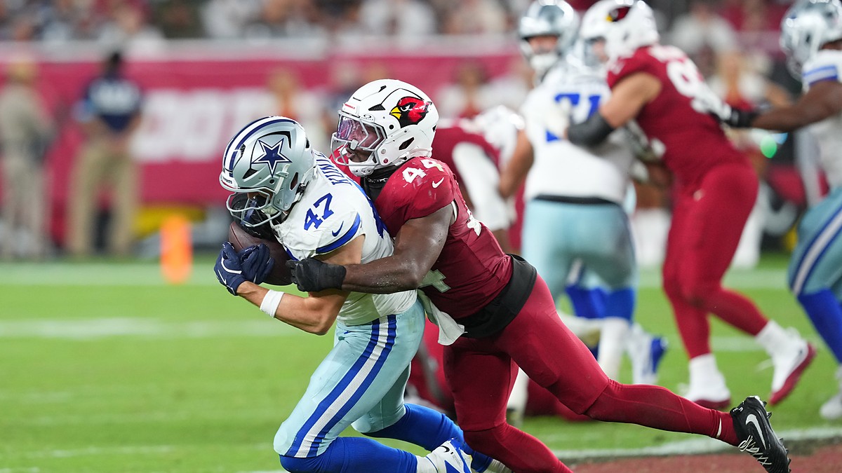 Dallas Cowboys tight end Zack Kuntz holds the ball as Cardinals linebacker Owen Pappoe wraps him up.