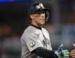New York Yankees right fielder Aaron Judge smiles and reaches out to slap hands with a teammate.