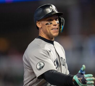 New York Yankees right fielder Aaron Judge smiles and reaches out to slap hands with a teammate.