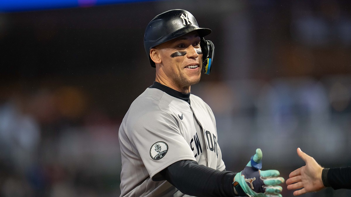 New York Yankees right fielder Aaron Judge smiles and reaches out to slap hands with a teammate.