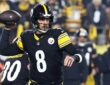 Pittsburgh Steelers quarterback Aaron Rodgers cocks the ball behind his head as he prepares to throw.