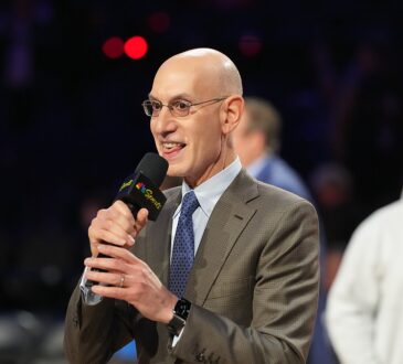 NBA commissioner Adam Silver holds a microphone and speaks on the floor after the All-Star Game.