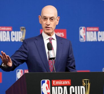 NBA commissioner Adam Silver gestures with one hand while speaking at an NBA Cup podium.