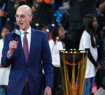 NBA commissioner Adam Silver speaks into a microphone beside the Emirates NBA Cup trophy on the court.