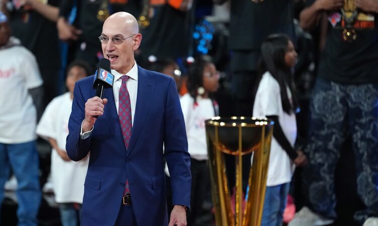 NBA commissioner Adam Silver speaks into a microphone beside the Emirates NBA Cup trophy on the court.