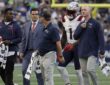New England Patriots wide receiver A.J. Brown walks on the field alongside four Patriots staff members.