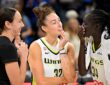 Dallas Wings forwards Alanna Smith, Jessica Shepard, and Awak Kuier laugh together on the court after a game.