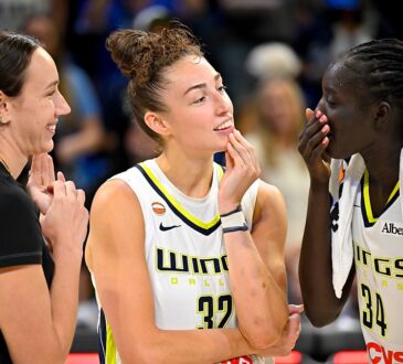 Dallas Wings forwards Alanna Smith, Jessica Shepard, and Awak Kuier laugh together on the court after a game.