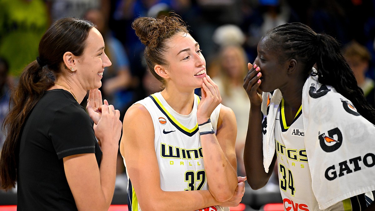 Dallas Wings forwards Alanna Smith, Jessica Shepard, and Awak Kuier laugh together on the court after a game.