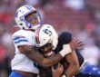 SMU Mustangs linebacker Alexander Kilgore tackles Stanford Cardinal quarterback Ashton Daniels around the shoulders.