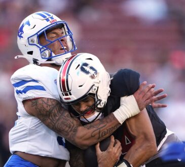 SMU Mustangs linebacker Alexander Kilgore tackles Stanford Cardinal quarterback Ashton Daniels around the shoulders.