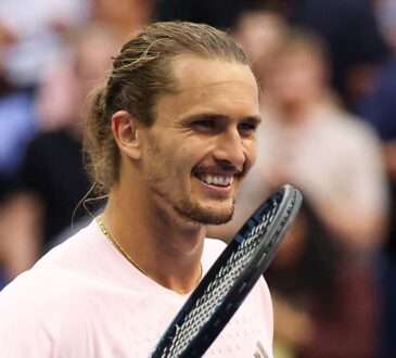 Alexander Zverev of Germany smiles with his racket raised beside his face after a match.